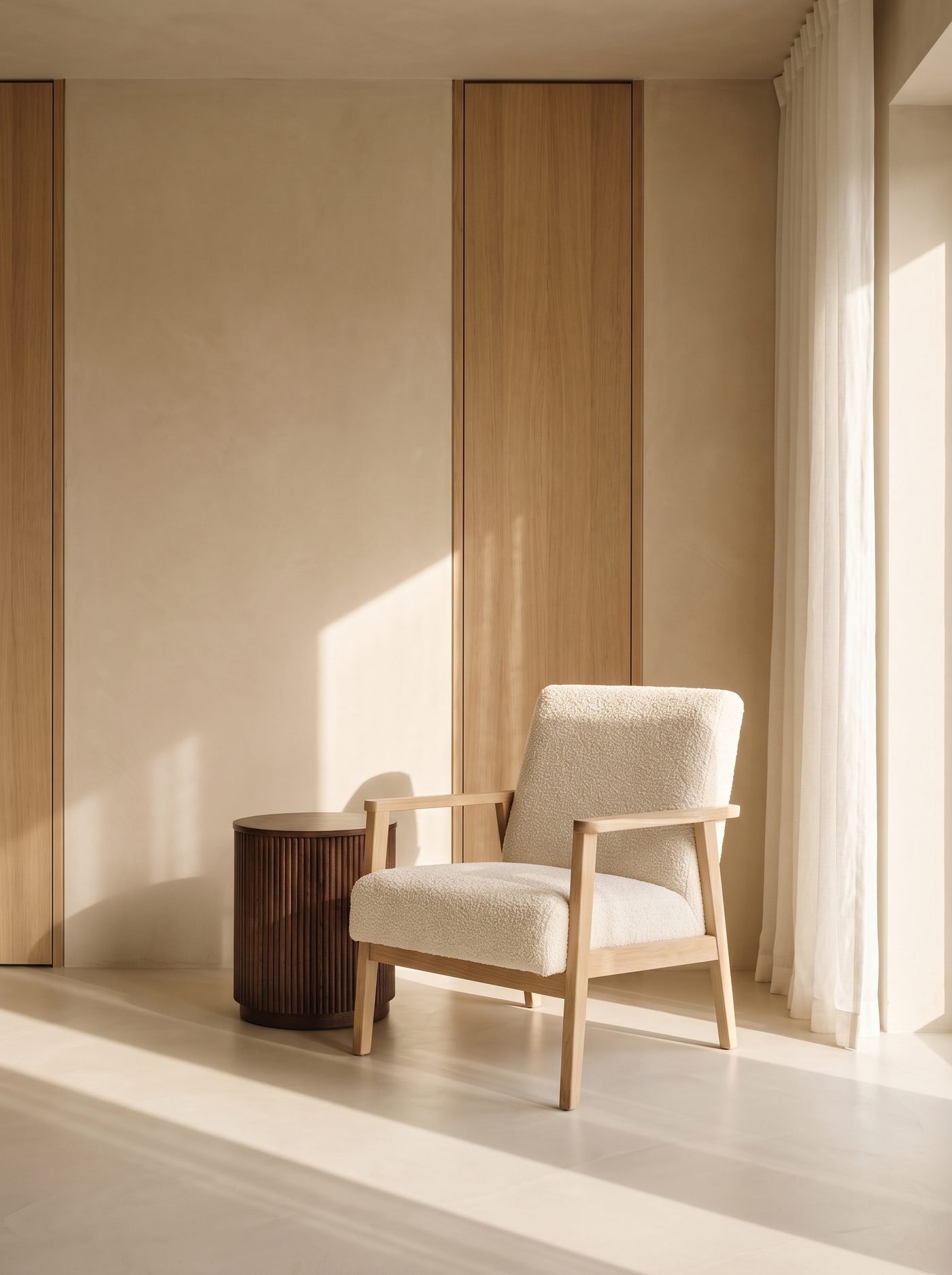 An oak and bouclé armchair beside a fluted side table in a sunlit room
